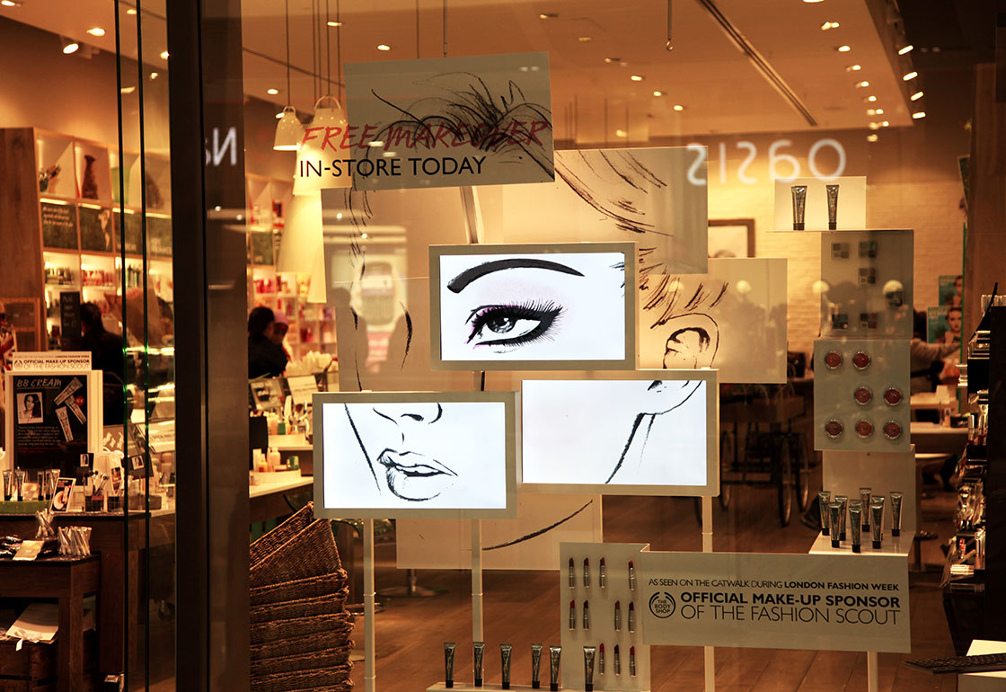 3 screens in a shop window showing an illustration of a women's face