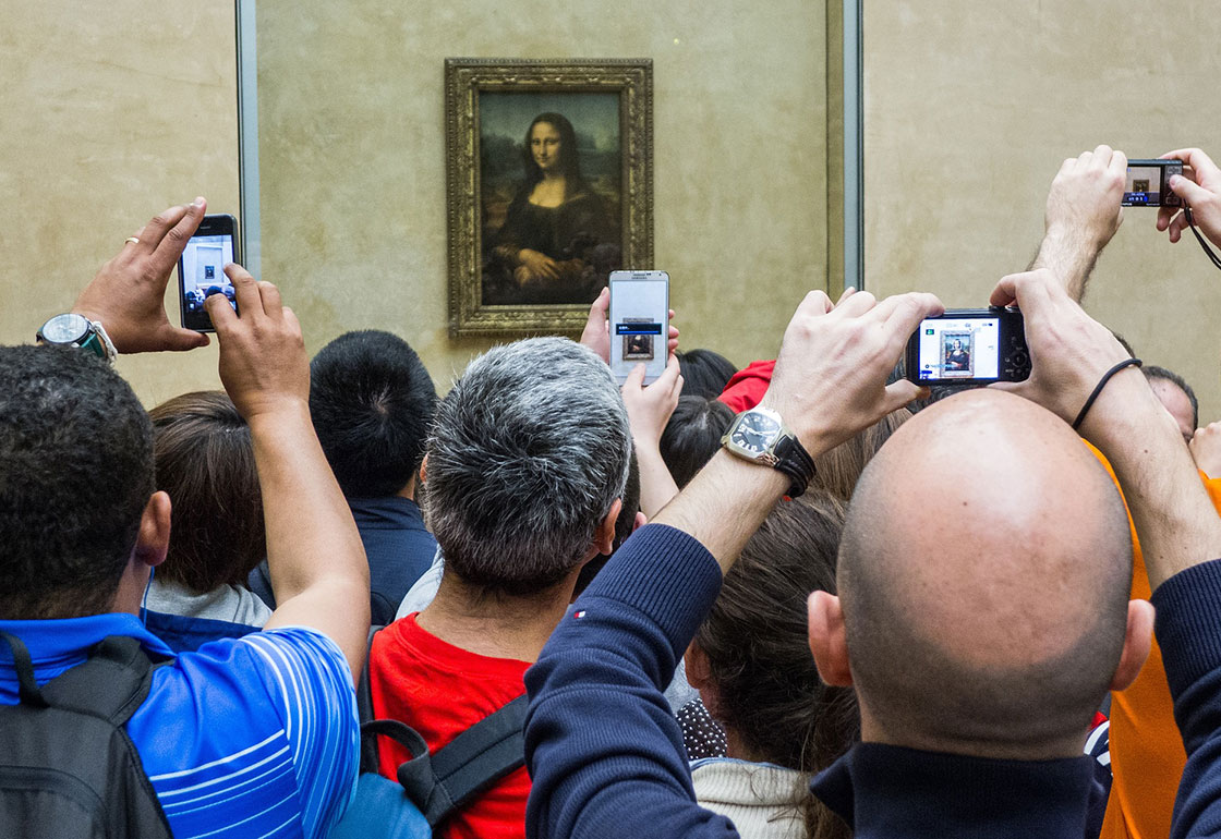 Visitors taking photos of the Mona Lisa at the Louvre on smartphones with facial recognition