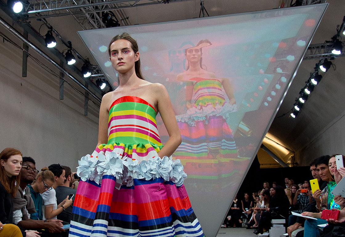 Model in bright clothes in front of a triangular screen