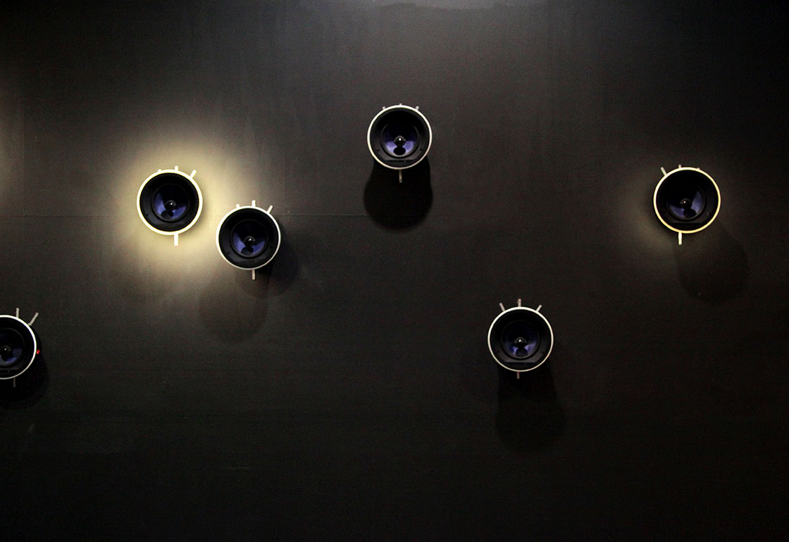 Speakers on a wall with one with a halo of light surrounding it