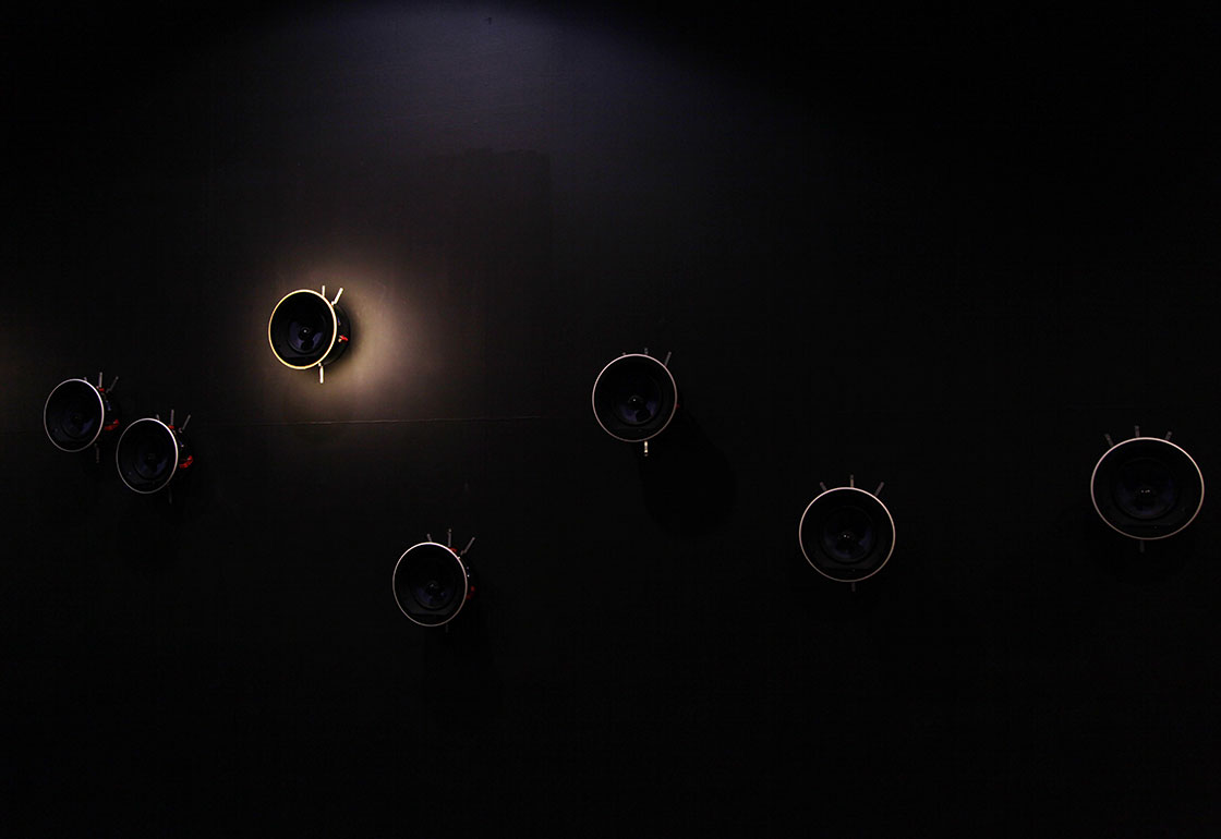 Speakers on a wall with one with a halo of light surrounding it